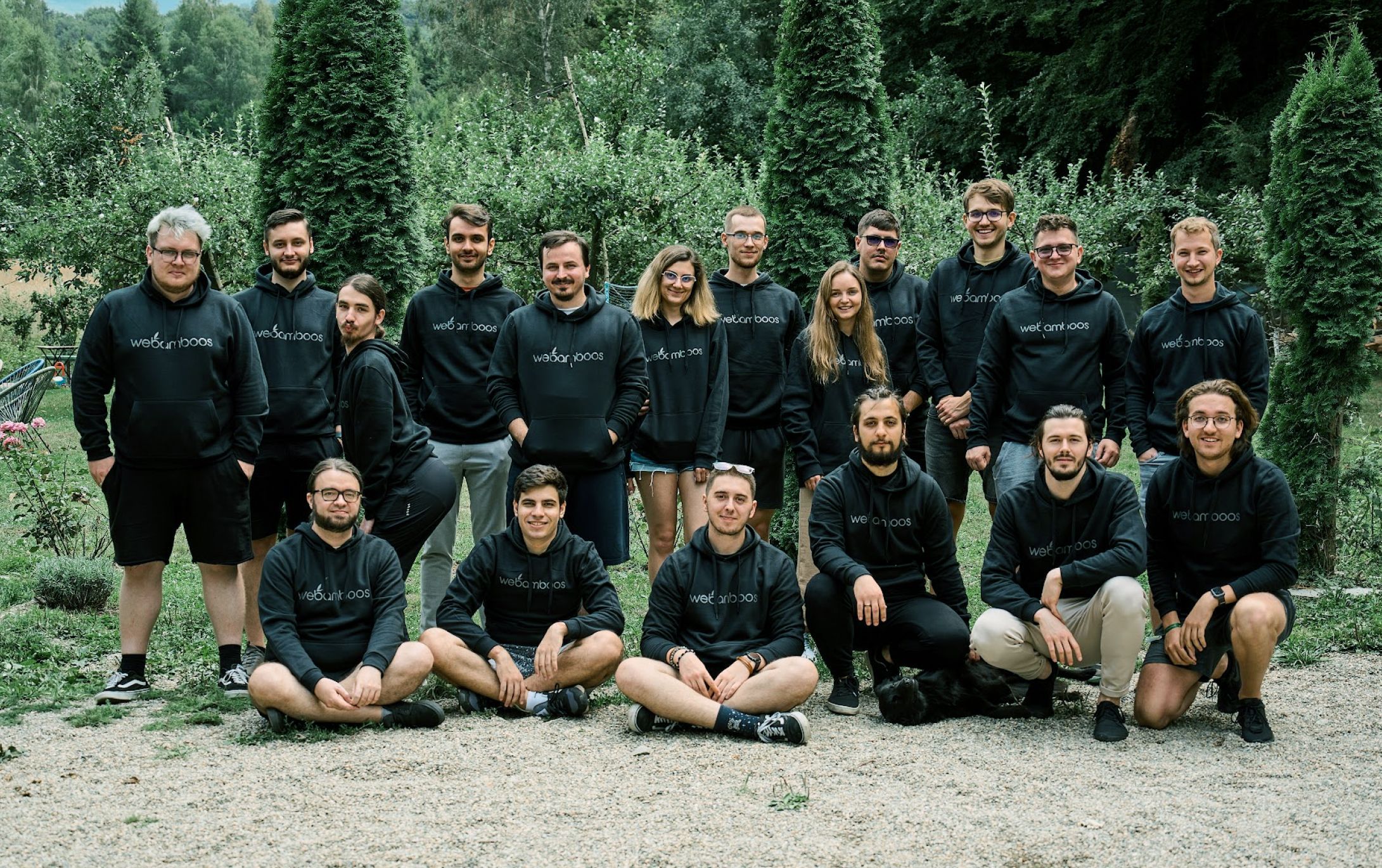 A group photo of a ~20 people in black hoodies with the Webamboos logo. Background is filled with nature.